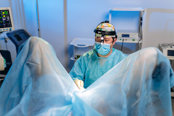 Professional male surgeon proctologist performing operation using special medical devices in the...