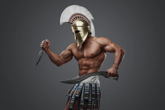Shot of naked antique soldier with plumed helmet and sword against gray background.