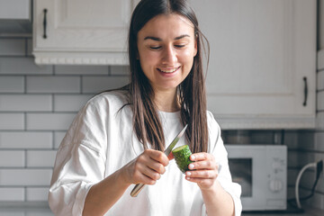 Attractive young woman cutting vegetables for salad in the kitchen.