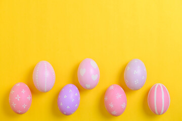 Happy easter holiday celebration concept. Group of painted colourful eggs decoration on a yellow background. Seasonal religion tradition design. Top view, flat lay, copy space.