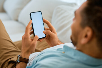 Close up of man texting on mobile phone while relaxing on sofa.