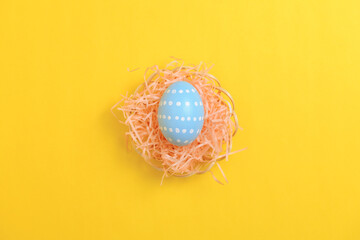 Happy easter celebration holiday. Blue pastel painted eggs in wicker basket nest decoration on a yellow background. Seasonal greeting gift card concept. Top view, flat lay, copy space.