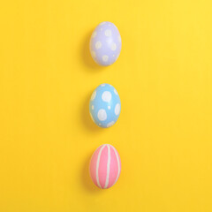 Happy easter holiday celebration concept. Group of painted colourful eggs decoration on a yellow background. Seasonal religion tradition design. Top view, flat lay, copy space.