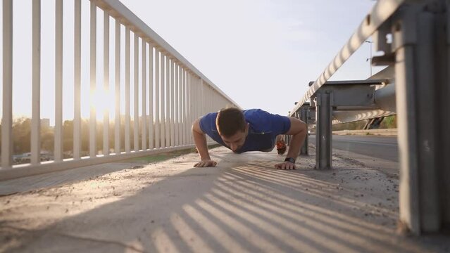 Sports and healthy lifestyle. Young man doing push-ups in city. Picture of a young athletic man doing push ups outdoors.