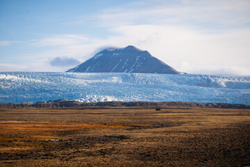 Obraz premium Majestic landscape with a mountain peaking up behind a glacier.