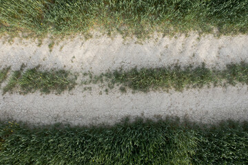 Drone scenery of secondary dry  rural road crossing a farmland meadow
