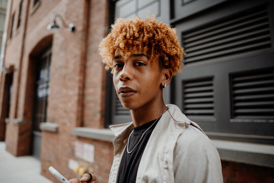 Portrait of the young african american man with serious expression leaning on the wall at street