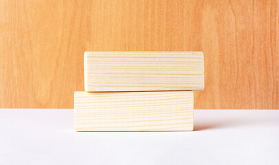 Two wooden jengas with a place for text insertion are depicted on a wooden and white background. Copy space