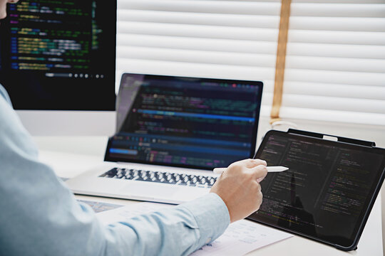programmer writing program code with two monitors Programmer analysis working with software code solving problems. developing software applications&nbsp;in the office