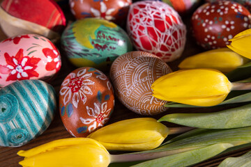 Colorful Easter eggs and yellow tulip flowers fill the entire frame.