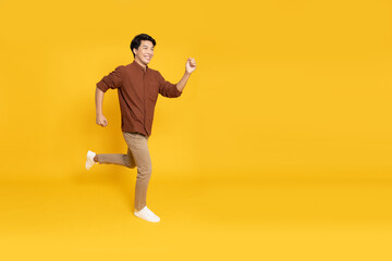 Side view of full length portrait of Asian young businessman walking isolated on yellow background - 580792541