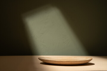 Wood plate in spot light, shadows on the wall. Background for food products cosmetics or jewelry....