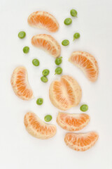 closeup the bunch ripe sliced orange fruit with green peas on the white background.