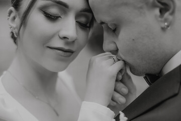the groom kisses the bride's hand, black and white photo, stylish brides. Delicate makeup. Wedding ring