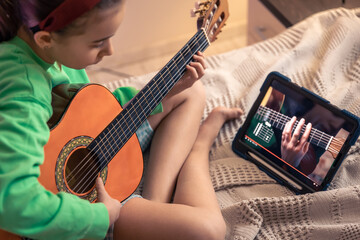 Little girl learns to play the guitar, online music video lesson.