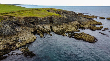 Fototapeta na wymiar A rocky cape on the Atlantic coast of Ireland. Seaside landscape. Green grass field beside body of water