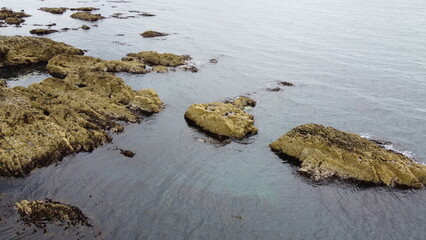 Rocky shore, top view. Big rocks in the water. Seascape. Brown rock formation on body of water