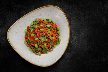 Buckwheat noodles with duck, vegetables and hot pepper on a plate