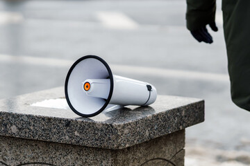 A hand-held loudspeaker lies granite pedestal for protest actions