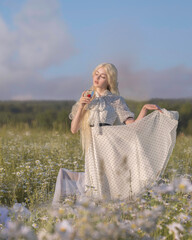 Albino girls in a vintage dress with a glass dancing in a field of daisies at sunset