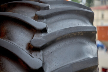 A photo of a fragment of a huge tire wheel of a construction or agricultural automobile equipment in close-up from the front