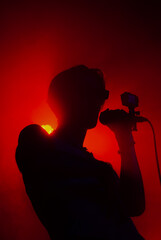 View on man with microphone on stage in red lights