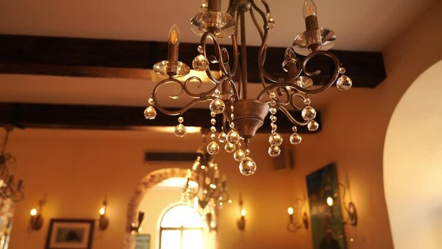 Bronze chandelier with crystal pendants and swirls hangs on the ceiling in the house