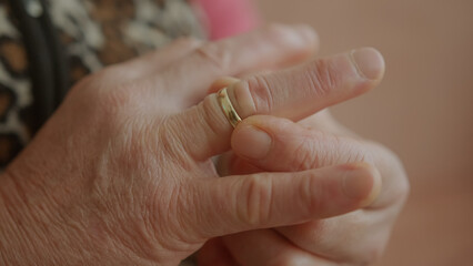 Timeless Elegance: Close-Up of Elderly Woman's Hands Adorning a Golden Ring