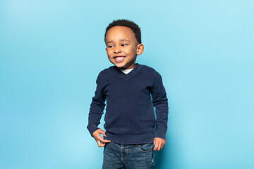 People, childhood, joy and happiness concept. Adorable black boy being in good mood, posing on blue...