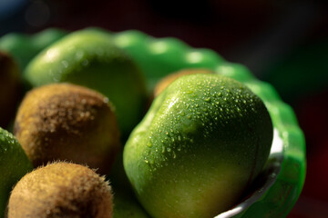 Wet green apples and kiwis. Fresh apples and kiwi on the table. Juicy fruits are ready to eat