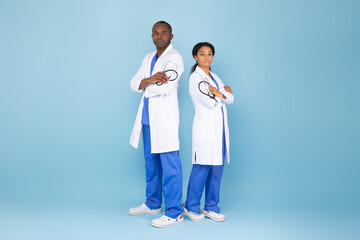 Photo of serious black male and female doc professionals posing with folded arms, wearing lab...