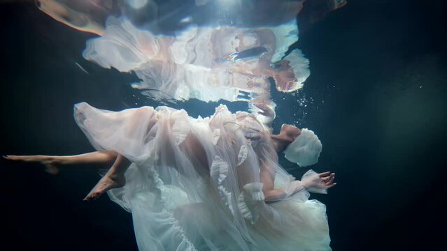 a delightful sight of a mysterious girl in a white dress under the water like a mermaid
