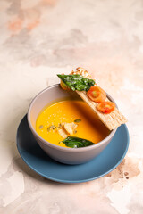 bright yellow pumpkin soup with seeds in a plate on the table