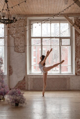 professional ballerina in a white gymnastic leotard is dancing in a room