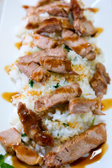 rice with greens meat and teriyaki sauce on rectangular white plate close-up lunch dinner hearty meal calories