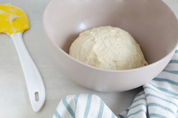 A bowl with dough and a cooking spatula on the table. The process of making Pampushky, traditional Ukrainian buns for borsch. The concept of traditional dishes. Homemade baking. Horizontal orientation