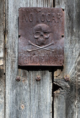 Antiguo cartel anunciando no tocar, peligro de muerte, colocado sobre una puerta