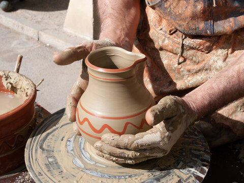 Un alfarero trabajando con sus manos sobre una vasija.