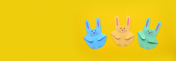 Banner. Easter craft from the imprint of a child's palm. Easter bunnies made of colored paper on a yellow background