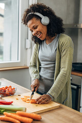 Cheerful mixed race woman prepares vegetables for cooking