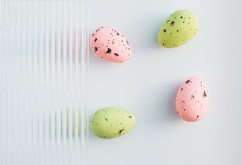 Modern composition made of pastel green and pink Easter eggs on grey background. Embossed glass texture background. Minimal festive concept. Abstract Easter card. Copy space.
