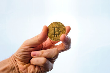 Man's hand holding a bitcoin coin, on a white background.