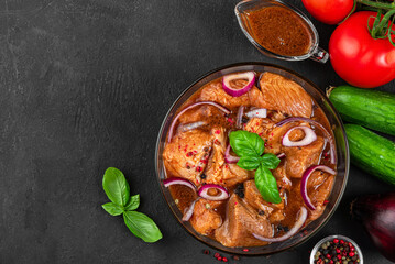 Raw pork or beef meat in marinade with vegetables on black background. Top view. Cooking food for...