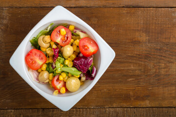 Fototapeta na wymiar Vegetable salad with champignon corn and cherry tomato with avocado in a white plate. save a place.