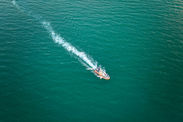 Aerial view of white yacht swimming on sea waves with ripple surface. Motor boat in motion on ocean