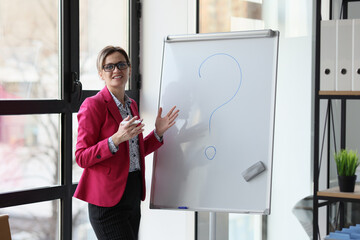 Female manager in glasses standing near whiteboard with question mark in office.