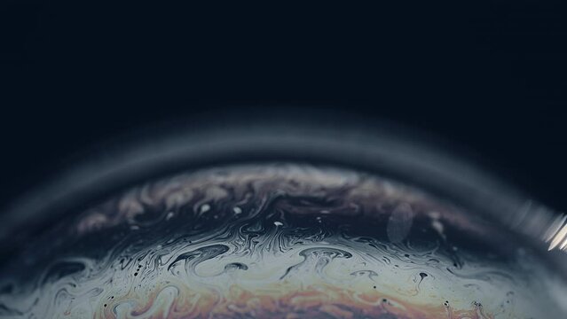 Soap bubble as a virtual grey alien planet in universe on dark background. Abstract soap bubble as an alien futuristic planet.