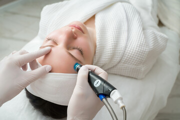A woman receives laser treatment of the face in a cosmetology clinic, a concept of skin...