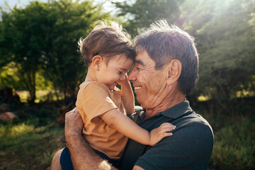 Playful grandfather spending time with his grandson in park on sunny day - Powered by Adobe