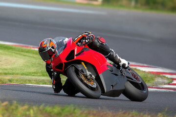 a motorcycle rider on a red sport bike riding through a corner at high speed, leaning the bike,...